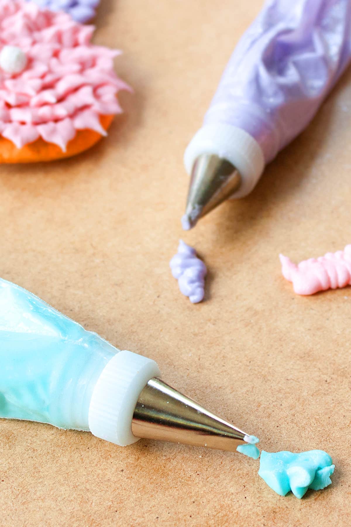 Piping bags filled with colored cookie icing that dries hard on wood background. 
