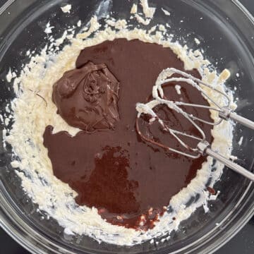 Glass bowl with creamed butter and shortening, melted chocolate and chocolate flour mixture. 