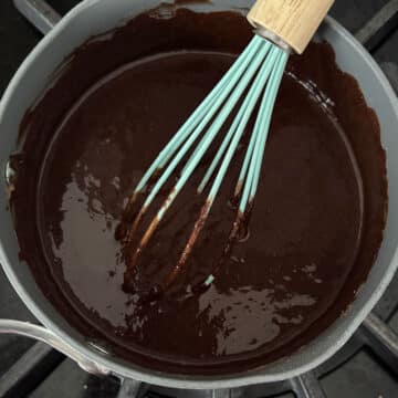 Melted chocolate flour mixture in saucepan with whisk. 