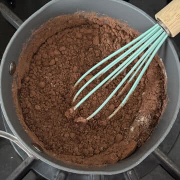 Flour, cocoa powder, sugar and milk in saucepan with whisk.