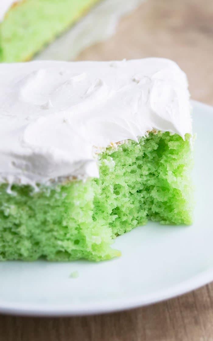 Homemade Pistachio Pudding Cake With Spoonful Removed on White Plate