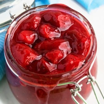 Easy Homemade Strawberry Pie Filling in Glass Jar With White Marble Background.