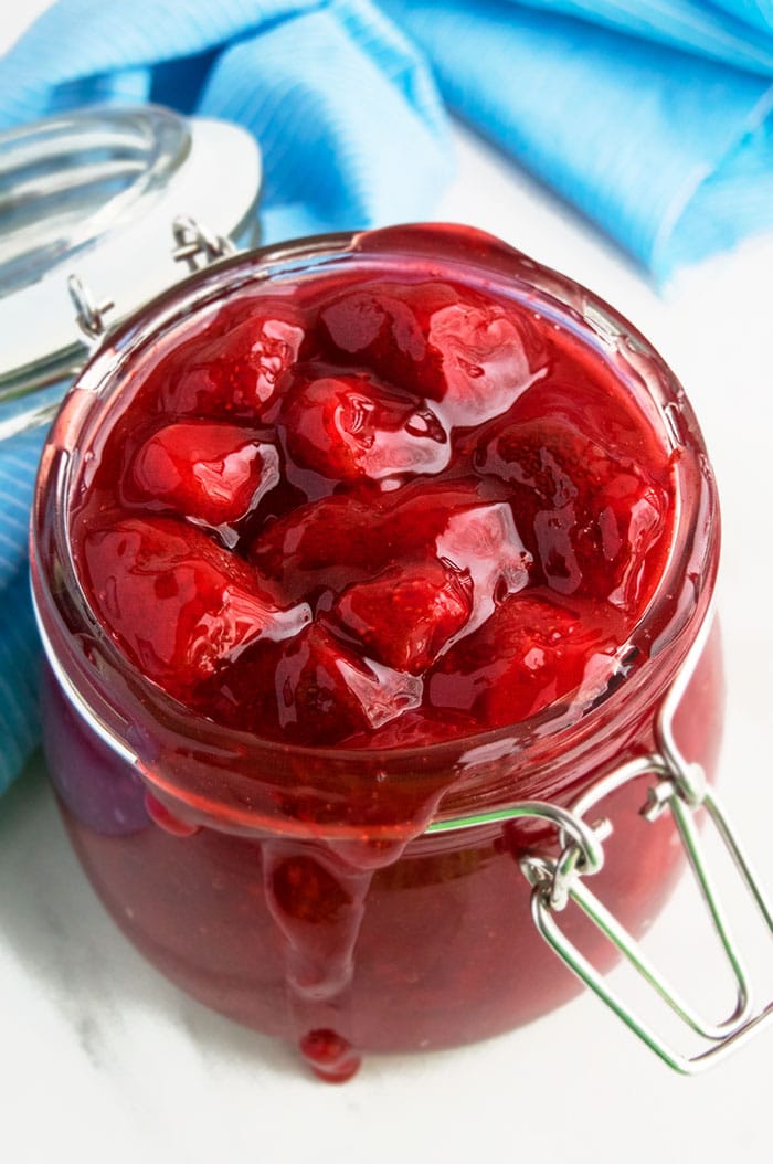 Easy Homemade Strawberry Pie Filling in Glass Jar With White Marble Background. 