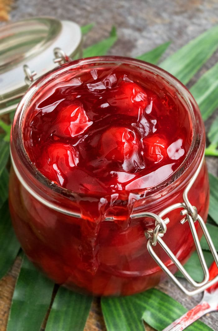 Homemade Cherry Filling in Glass Jar on Green Leaf