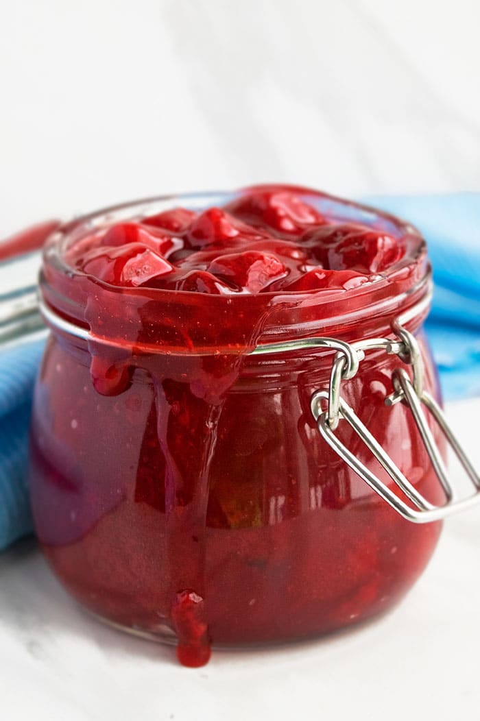 Fresh Berry Filling In Glass Jar on White Marble Background. 