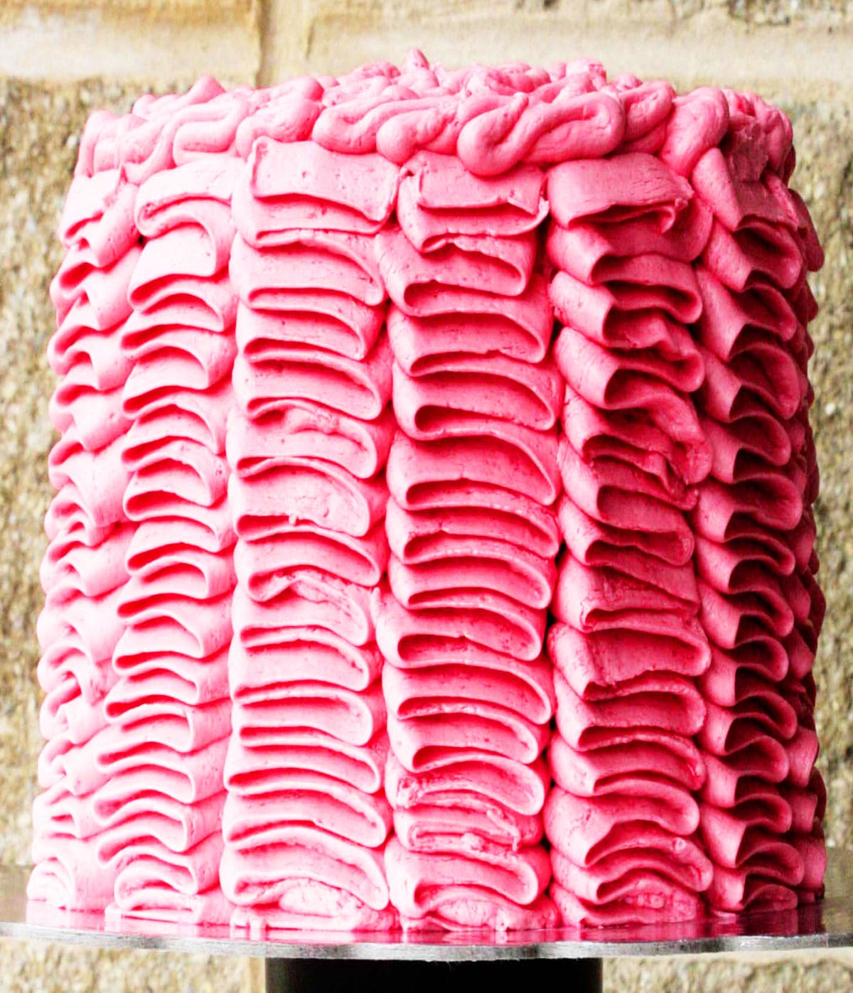 Decorated Pink Cake on Cake Stand with Brick Background.