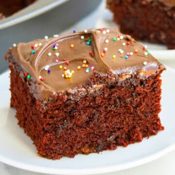 Slice of Wacky Chocolate Depression Cake With Frosting on White Dish.