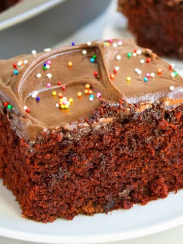 Slice of Wacky Chocolate Depression Cake With Frosting on White Dish.