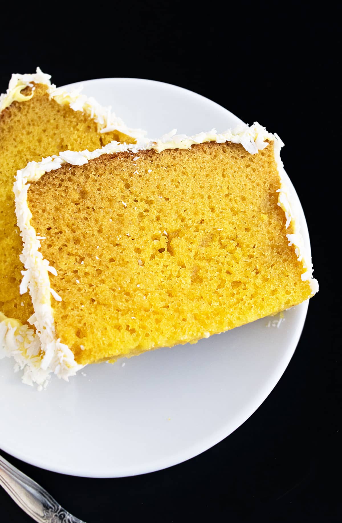 Slices of frosted loaf cake on white dish. 