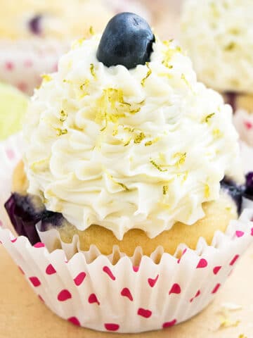 Best easy soft and moist frosted lemon blueberry cupcakes with pink polka dot liners on light brown background.