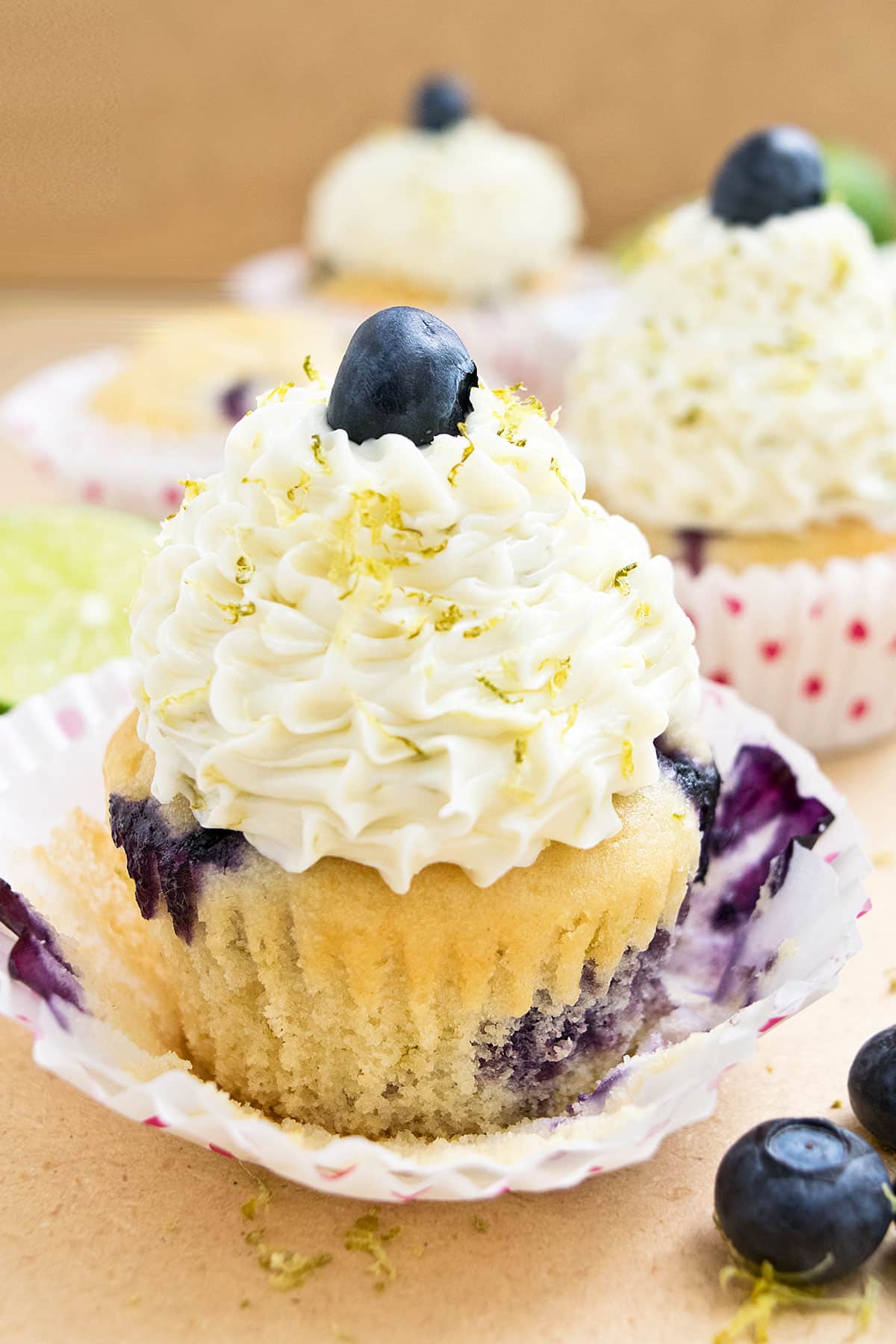 Easy homemade frosted lemon blueberry cupcakes with liner partially peeled.