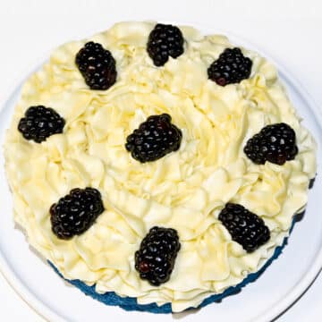 Blackberries placed on top of yellow frosted cake.