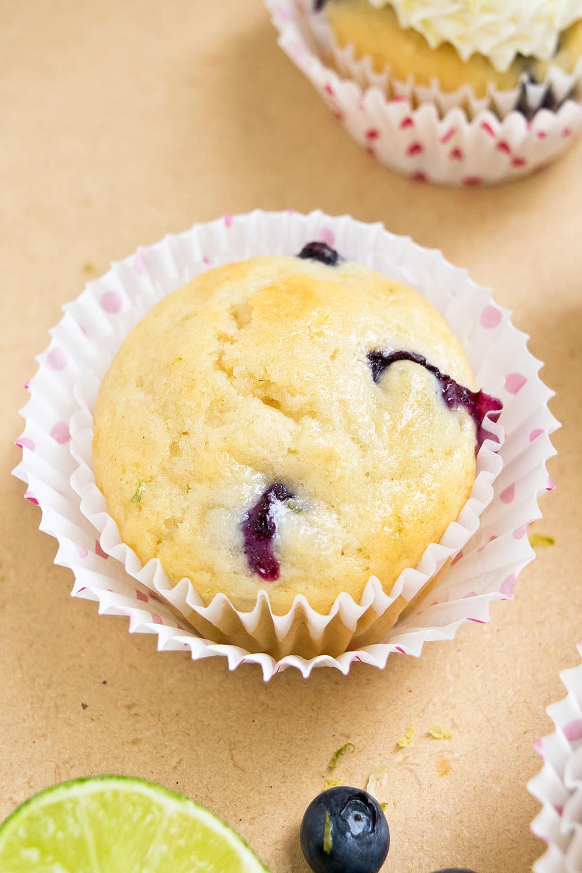 Unfrosted cupcake in polka dot liners on light brown background.