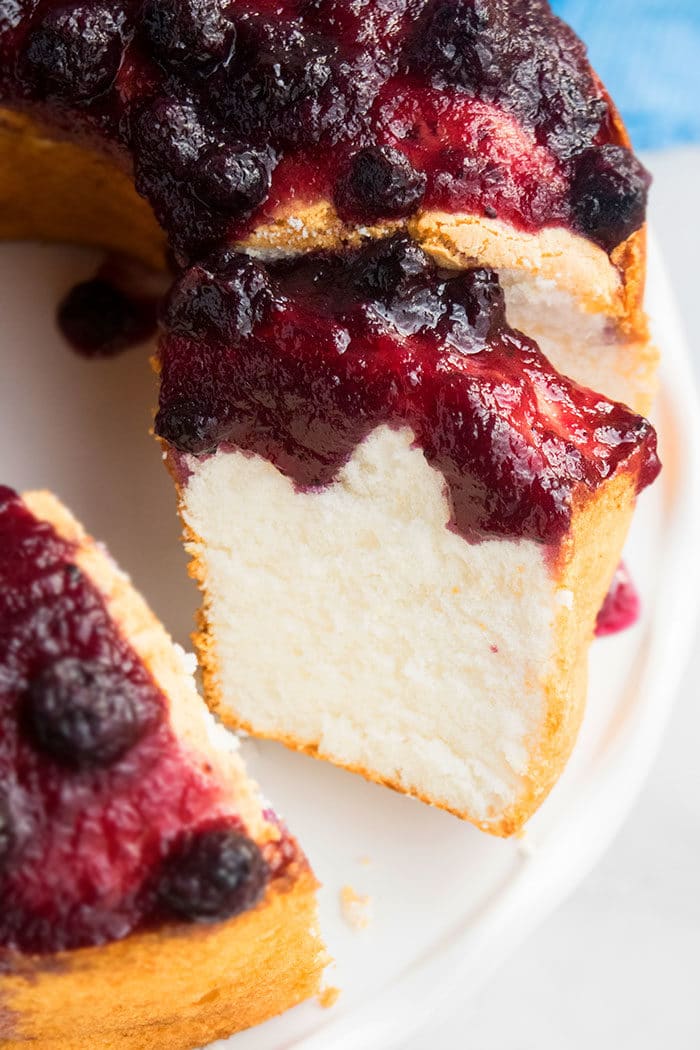 Slice of Angel Food Cake From Scratch With Blueberry Topping on White Cake Stand. 
