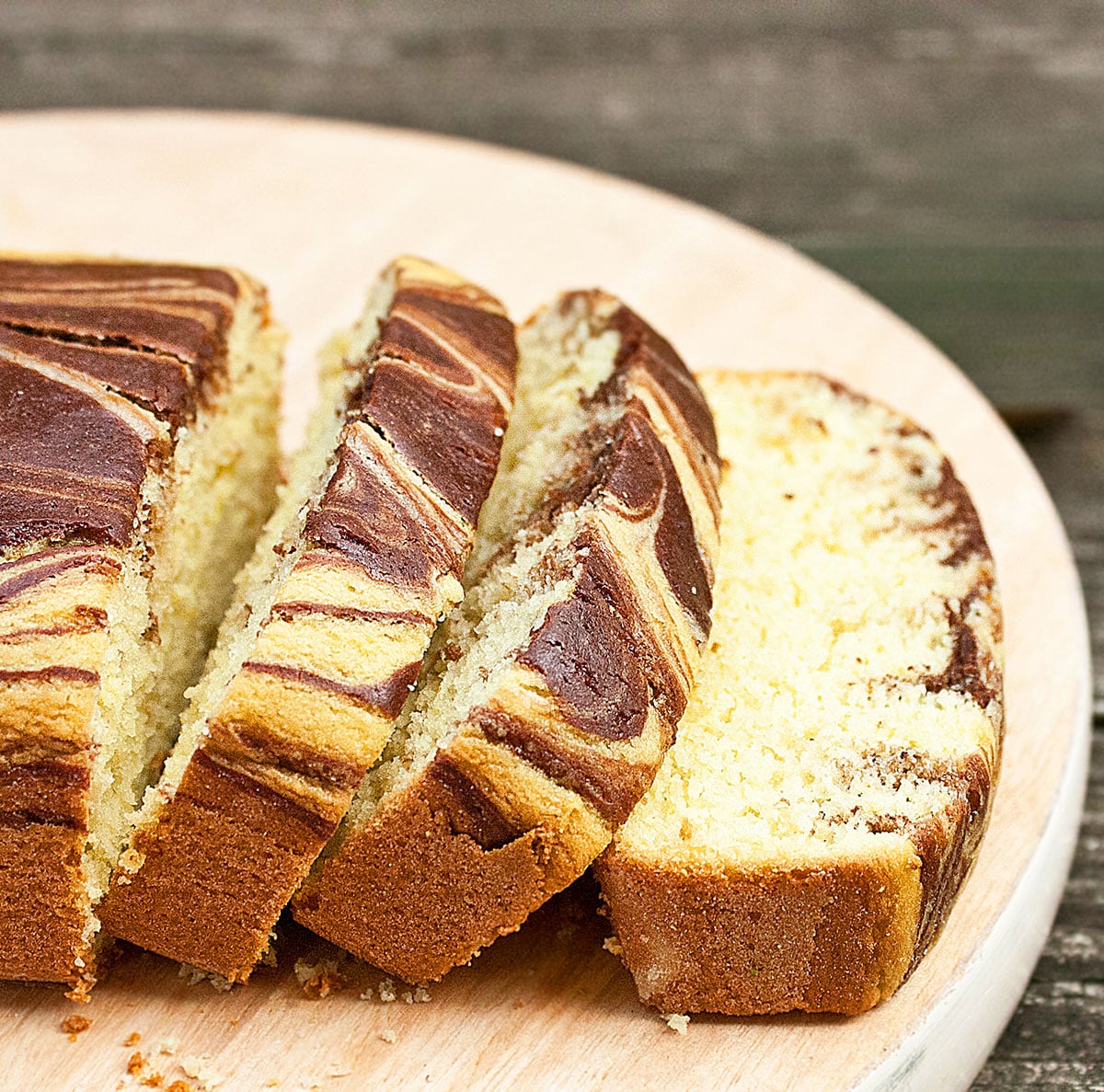 Closeup shot of slices of loaf cake on round wood dish. 