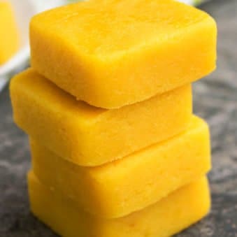 Stack of Easy 2 Ingredient Microwave Lemon Fudge on Rustic Gray Background.