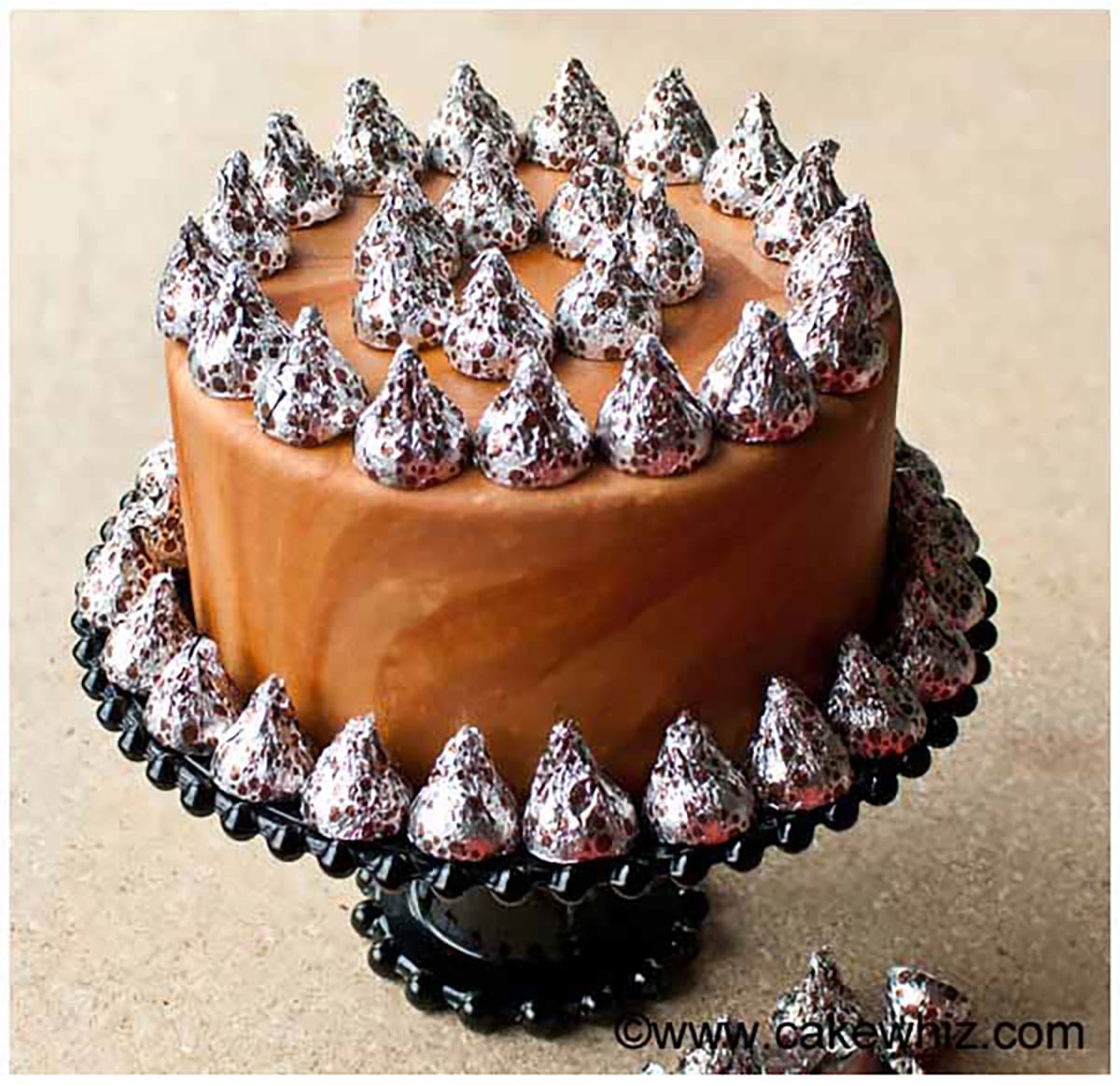 Fondant covered cake on black cake stand. 