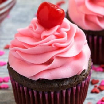 Easy Maraschino Cherry Frosting (Buttercream Icing) Piped on Top of Chocolate Cupcake on Rustic Gray Background.