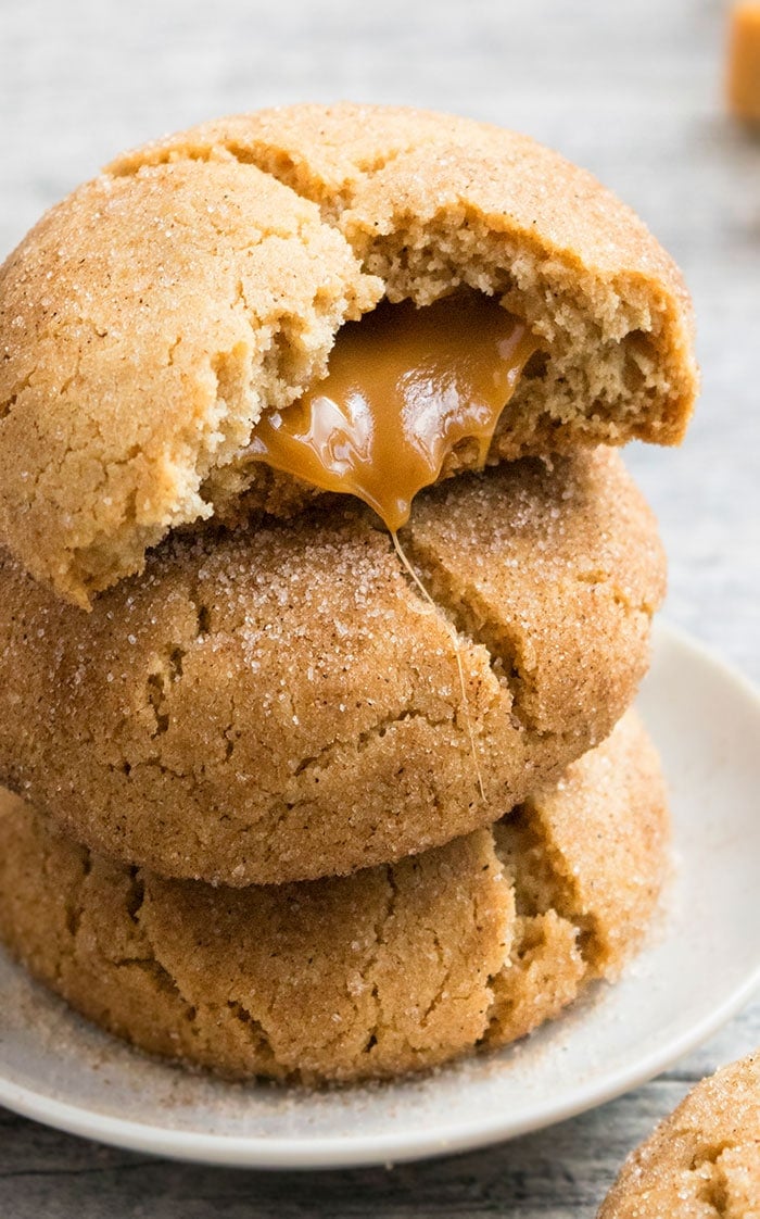 Stack of Stuffed Caramel Snickerdoodles on White Plate With Caramel Oozing Out.