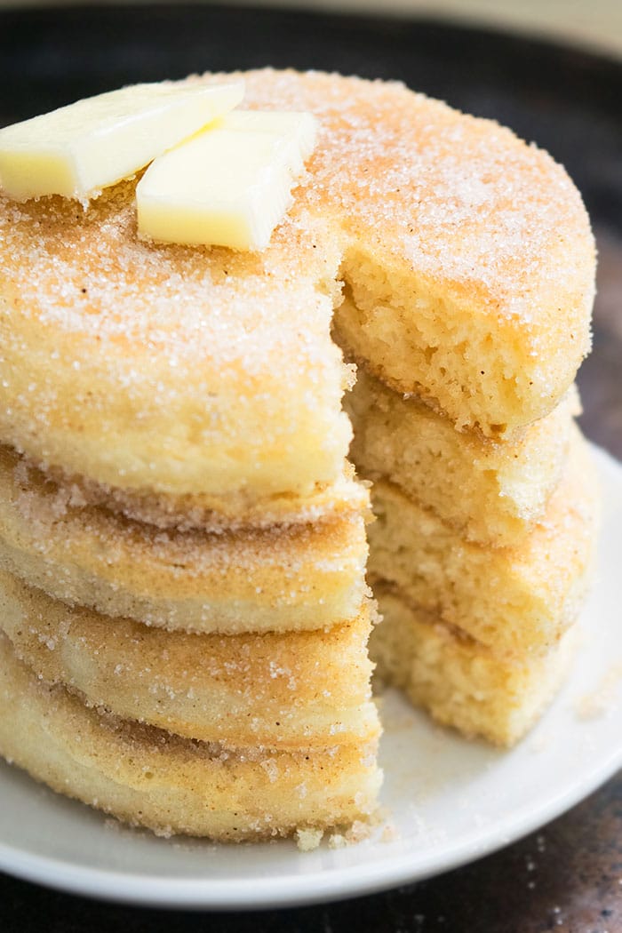 Stack of Fluffy Spiced Pancakes on White Dish With Big Slice Removed.  