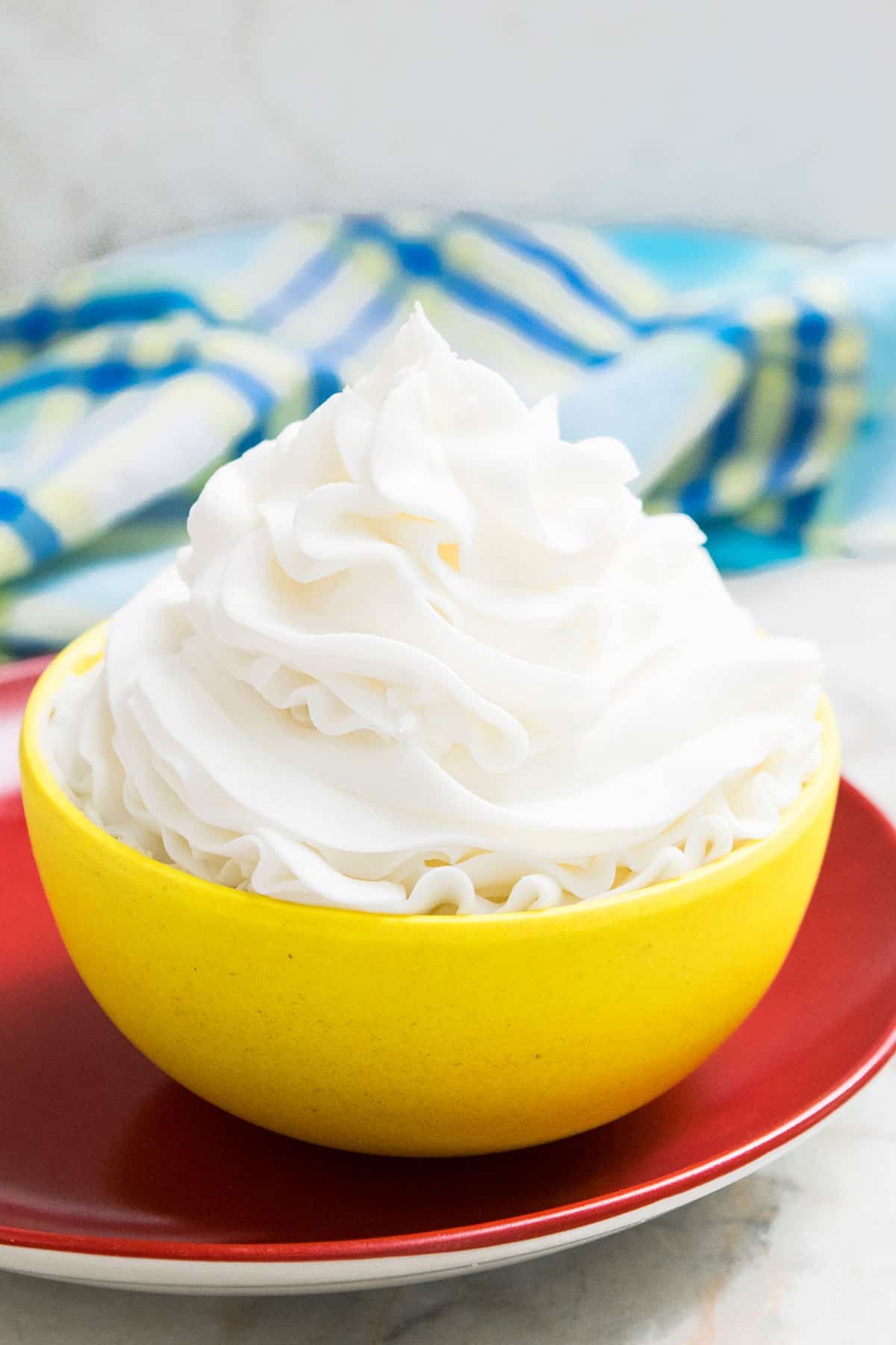 Best Easy Classic American Buttercream Frosting in Yellow Bowl on Red Dish. 