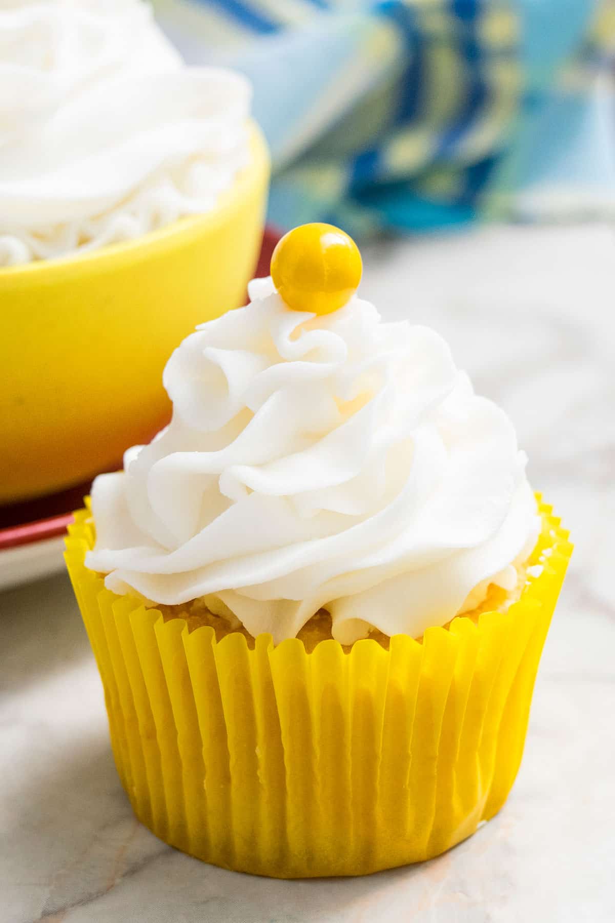 Frosted Cupcake With Yellow Candy Decoration on Marble Background. 
