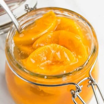 Easy Homemade Peach Pie Filling in Glass Jar on White Marble Background.