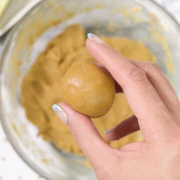 Dough balls being held in hand. 
