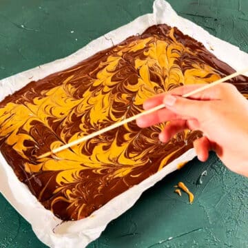 Peanut butter being swirled with a wooden skewer. 