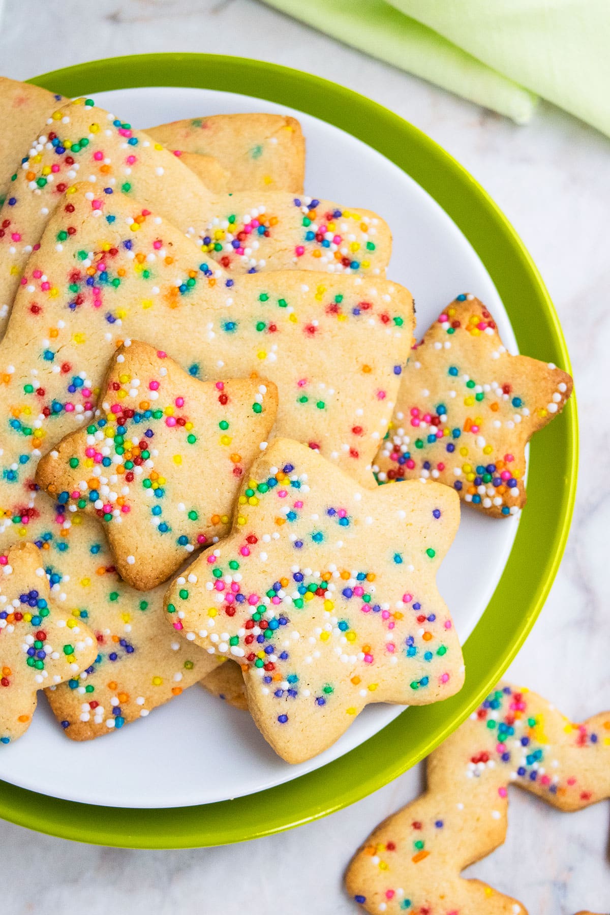 Cut out rainbow cookies with sprinkles on white and green dish. 