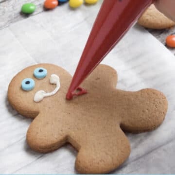 Cookie being decorated on sheet of wax paper. 