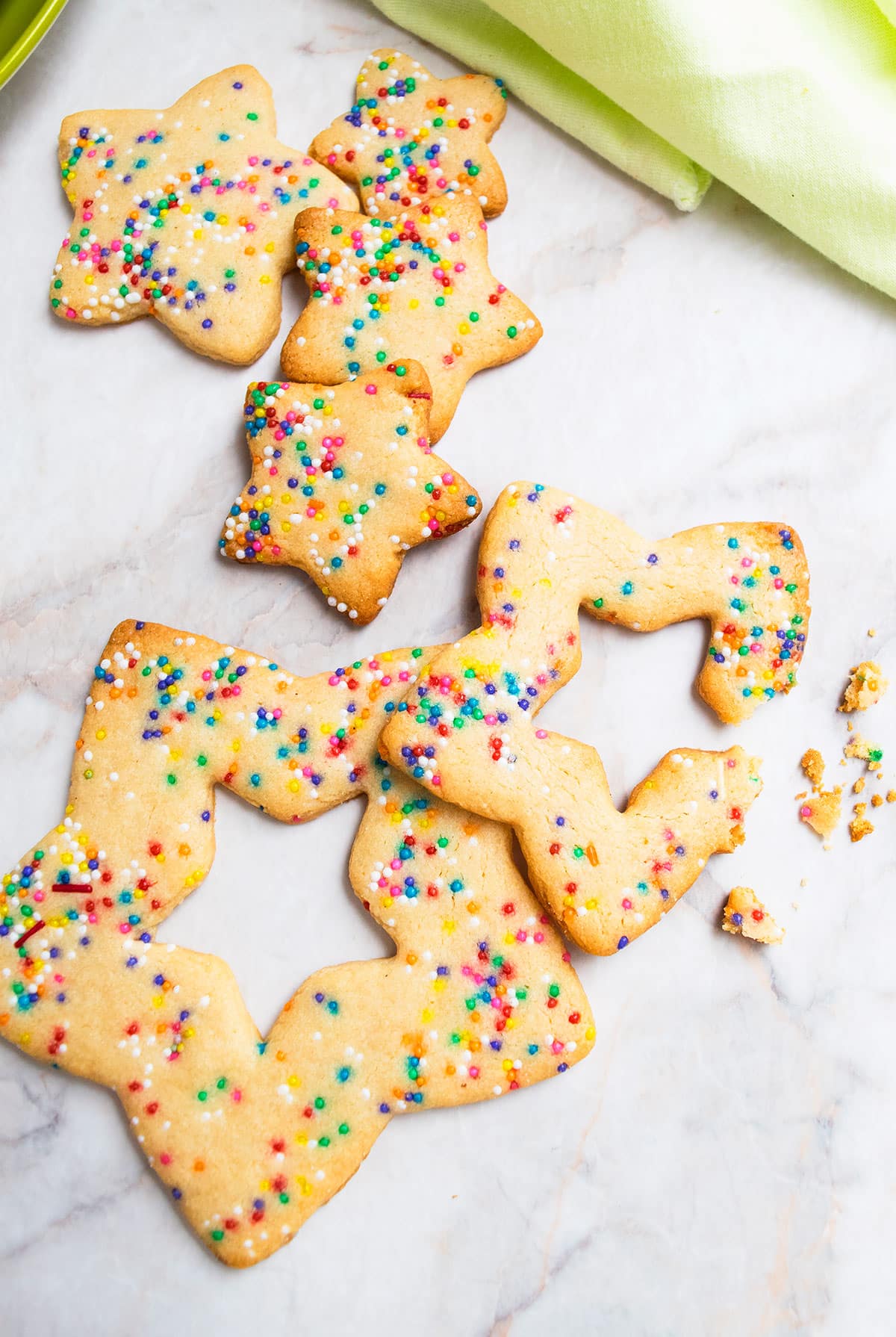 White marble background with many sizes of cookies and one is partially eaten. 