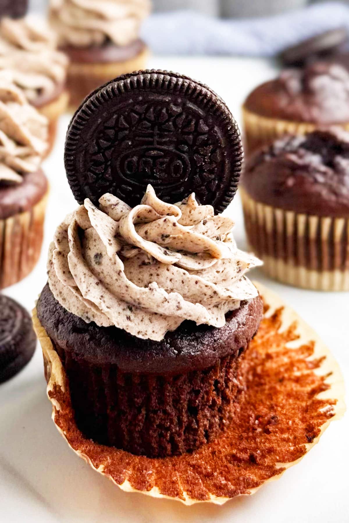 Frosted cupcake with liner partially peeled. 