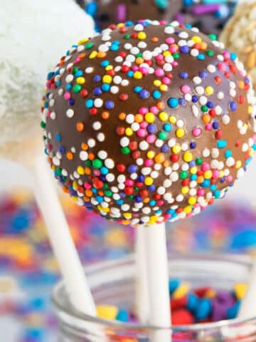 Easy Homemade Cake Pops Covered in Melted Chocolate and Sprinkles in Glass Jar.