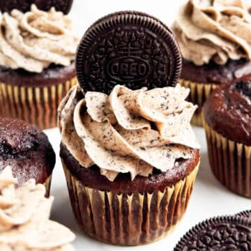 Easy chocolate Oreo cupcakes with cake mix that is topped with cookies and cream buttercream frosting on white marble background.