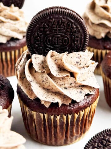 Easy chocolate Oreo cupcakes with cake mix that is topped with cookies and cream buttercream frosting on white marble background.