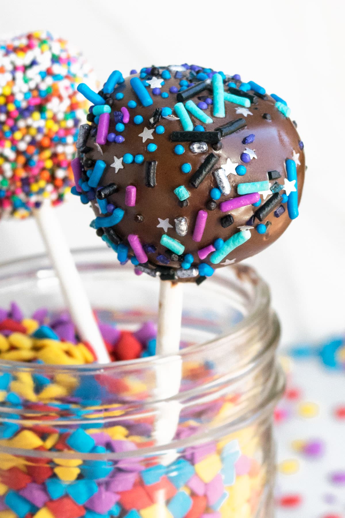 Galaxy themed dessert on a stick in jar of sprinkles. 