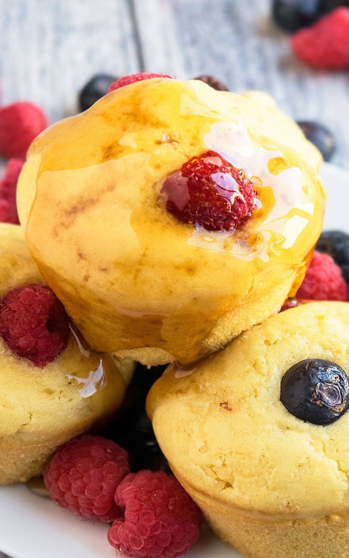 Stack of Easy Pancake Muffins With Fresh Fruits and Maple Syrup on White Dish.