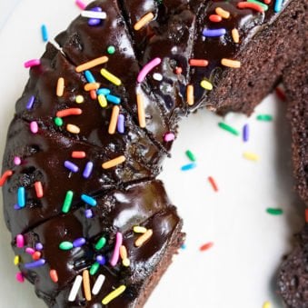 Easy Moist Chocolate Bundt Cake with Chocolate Ganache and Sprinkles on White Dish.