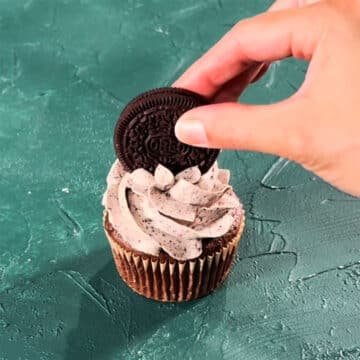Sticking a cookie on top of a frosted cupcake. 