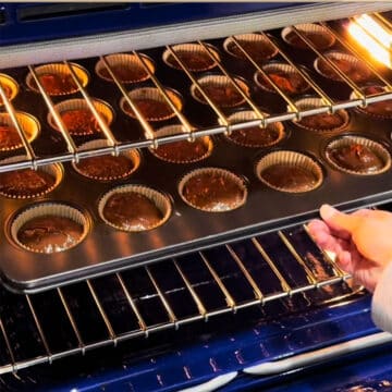 Cupcake tray being placed in oven for baking. 