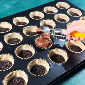 Batter being poured on top of cookies. 