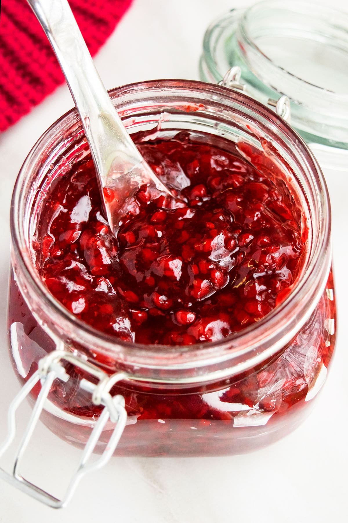 Best easy homemade raspberry pie filling with fresh or frozen raspberries in glass jar on white background. 