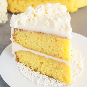 Slice of Best Vanilla Cake With Vanilla Buttercream Frosting on White Dish.