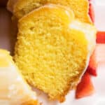Best easy lemon bundt cake with cake mix and topped off with lemon glaze on white dish.