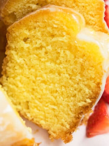Best easy lemon bundt cake with cake mix and topped off with lemon glaze on white dish.