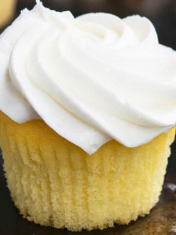 Easy Homemade Vanilla Cupcakes From Scratch With Vanilla Frosting on Rustic Tray.