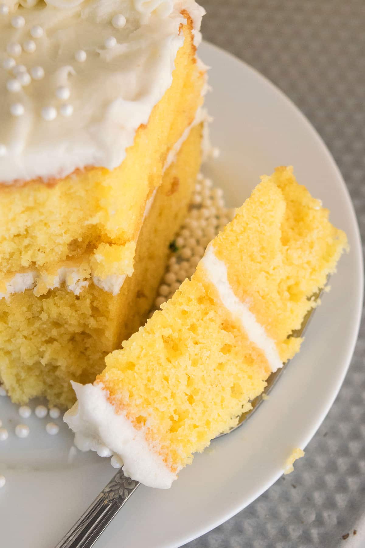 Fork full of cake on white cake dish. 