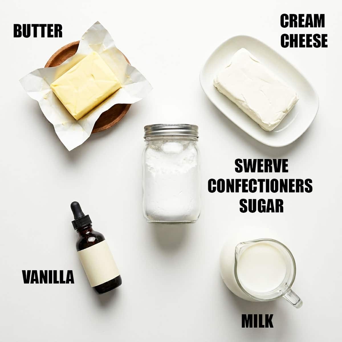 Ingredients for recipe on white background- butter, cream cheese, swerve confectioners sugar, vanilla extract and milk. 