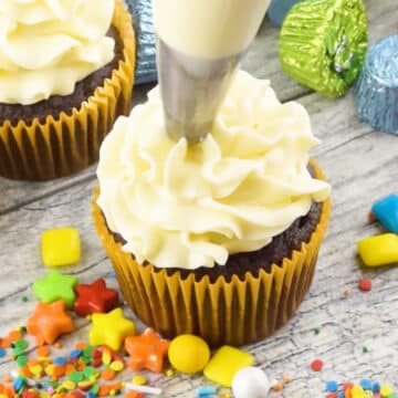 Icing being piped on top of chocolate cupcake. 